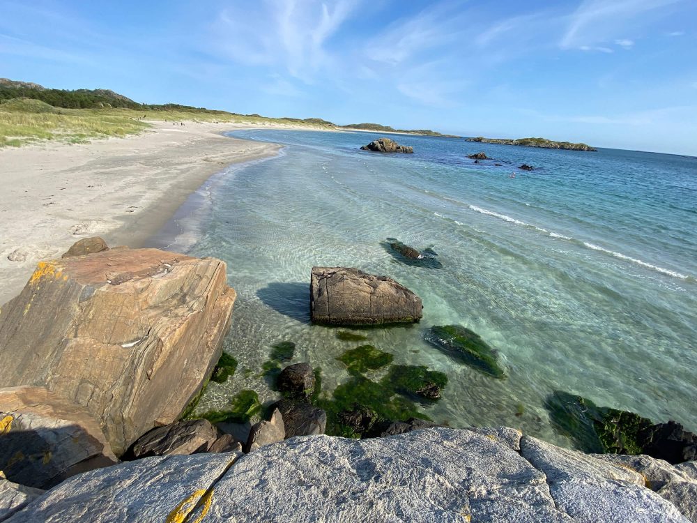 Fotovorlage eines Strandpanoramas in Südnorwegen mit Felsen, Sandstrand und türkisblauem Wasser im Sommer 2024.